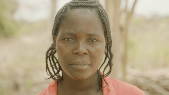 Veronica, une agente de santé au Mozambique, regarde la caméra. C'est une femme africaine aux cheveux tressés et une chemise rouge