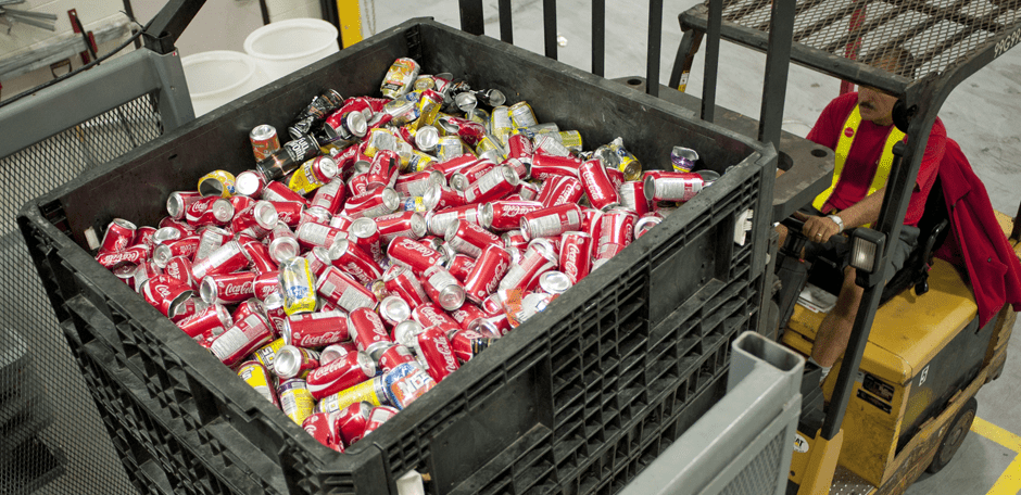 Un chariot élévateur à fourche qui soulève un conteneur avec beaucoup de canettes d'aluminium de Coca-Cola