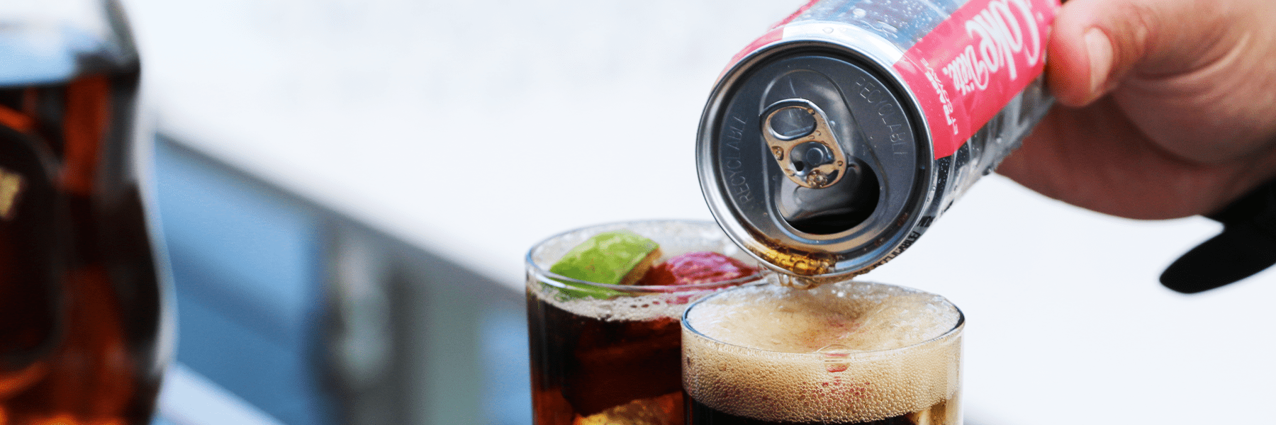 Une main versant du Coke Diète dans un verre